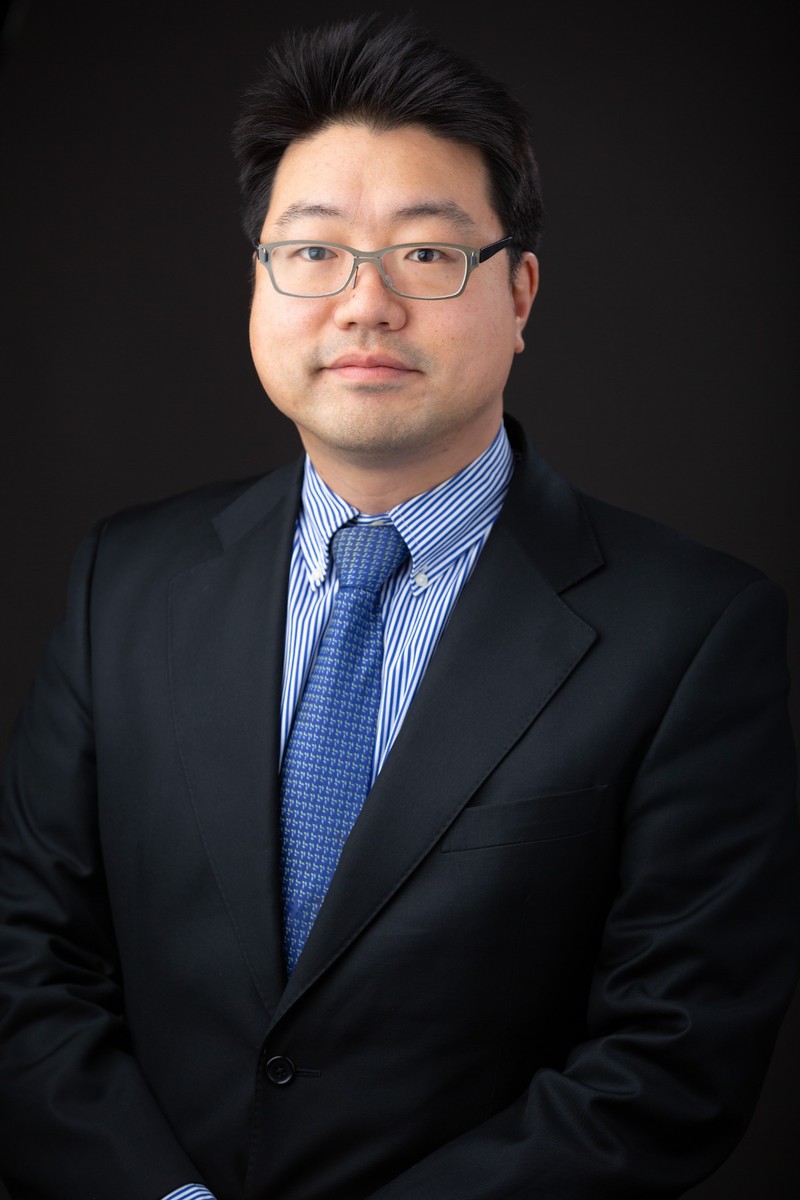Portrait of Chungwook Sim, Director of SIM Lab, wearing glasses and a dark suit.